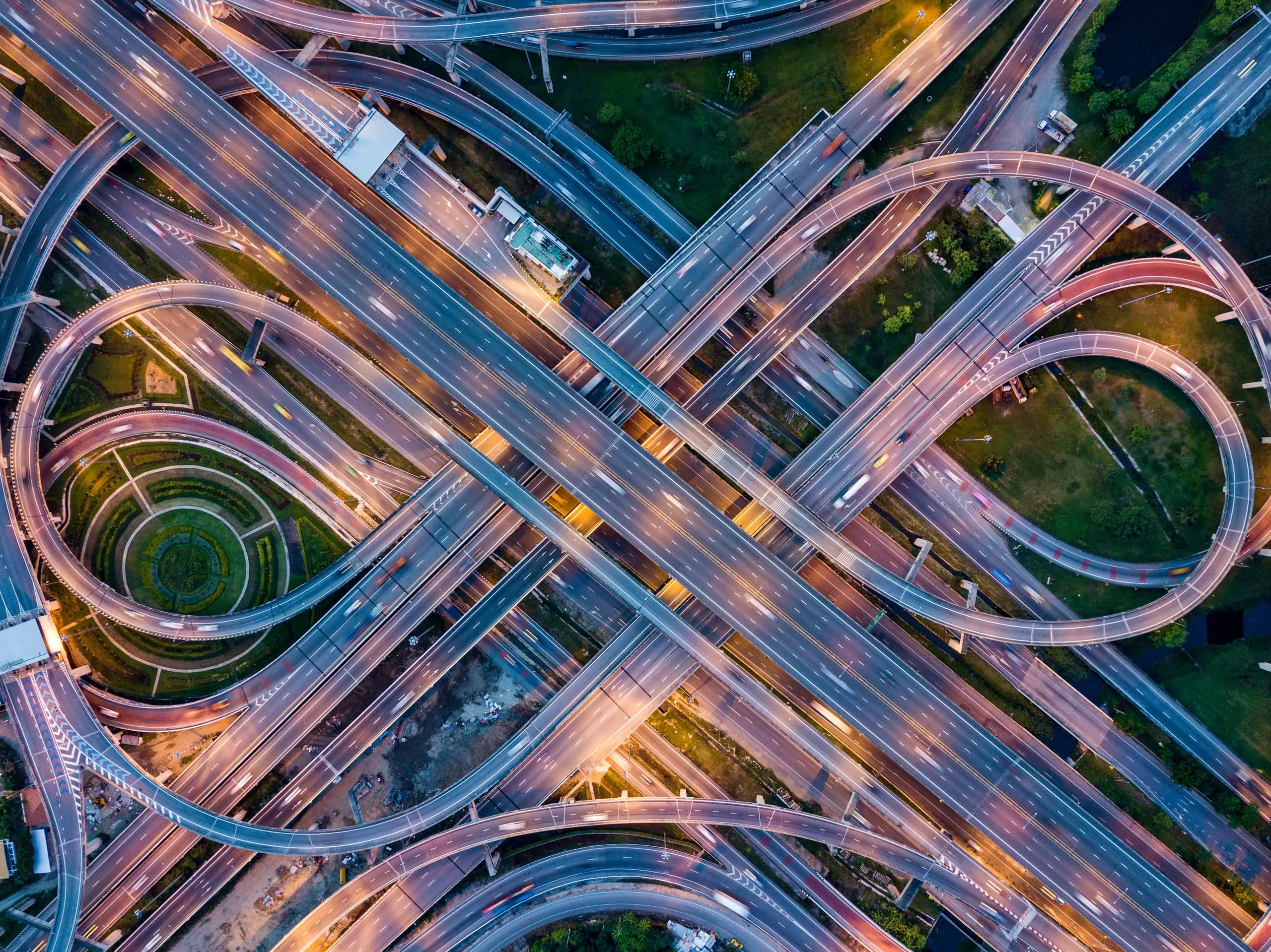 An aerial view of a complex highway interchange with many connected routes at dusk.